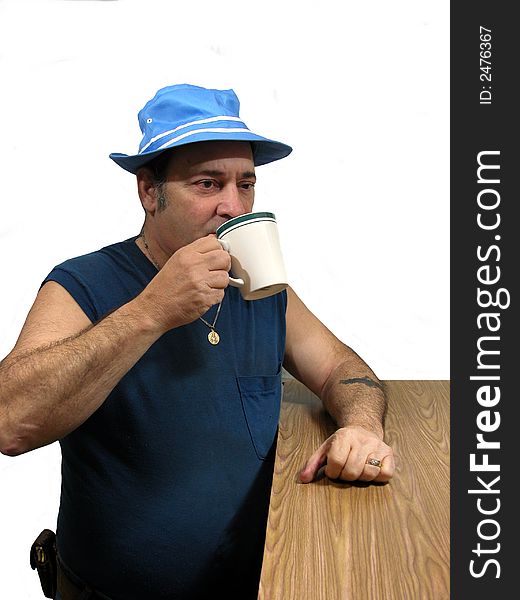 A man standing at a counter in a blue hat drinking a cup of coffee, over white. A man standing at a counter in a blue hat drinking a cup of coffee, over white