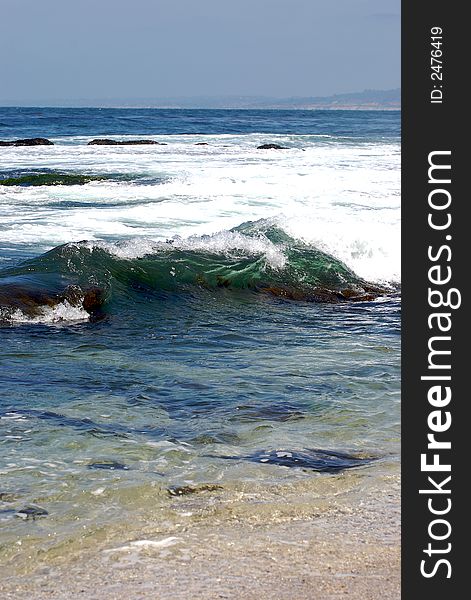 Wave on a sandy beach with a blue sky background