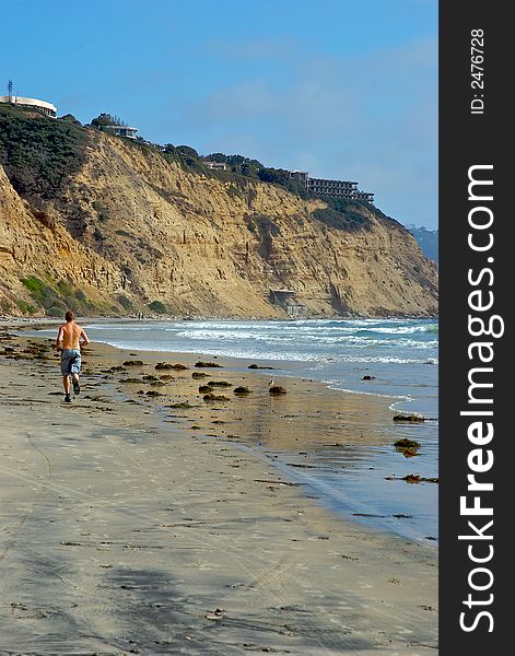 A man running on the beach with a blue sky background