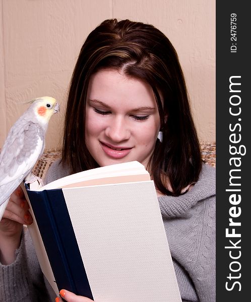 Attractive teen girl reading with her pet bird is perched on her book. Attractive teen girl reading with her pet bird is perched on her book.