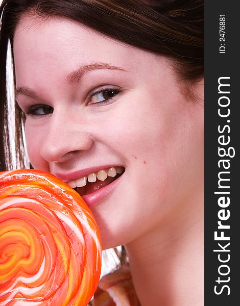 Attractive teen eating a giant lollipop.  Isolated on white.