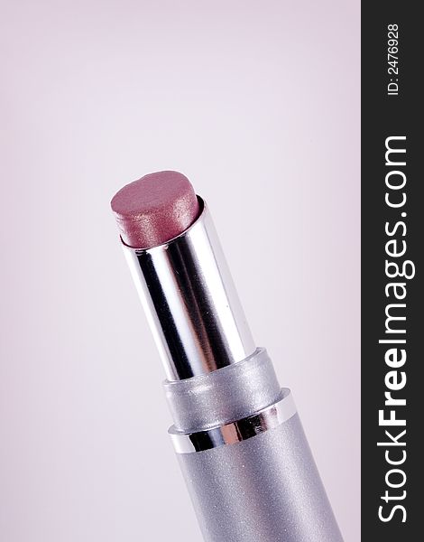 A tube of pink lipstick against a slightly pink vignetted background.