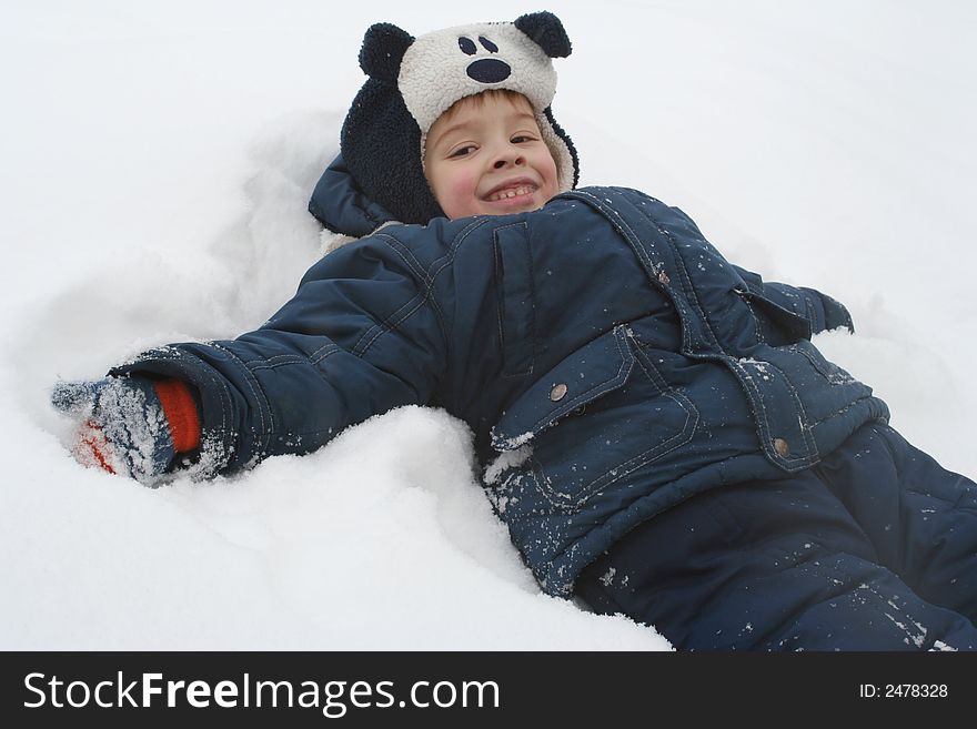 The boy lays on a snow