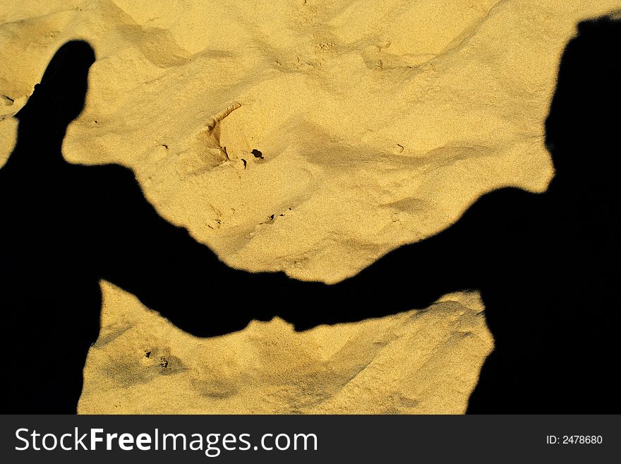 A photo of a couples's shadow in the sand. A photo of a couples's shadow in the sand.