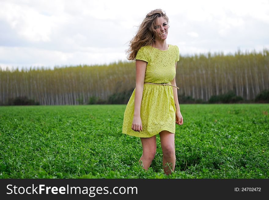 Portrait of a beautiful blonde girl, dressed with a green dress, standing in a meadow. Portrait of a beautiful blonde girl, dressed with a green dress, standing in a meadow