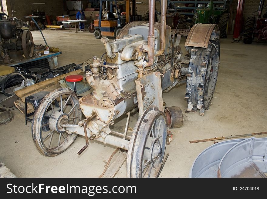 A very old vintage tractor in a untidy workshop. A very old vintage tractor in a untidy workshop