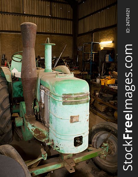 A very old vintage tractor in a untidy workshop. A very old vintage tractor in a untidy workshop