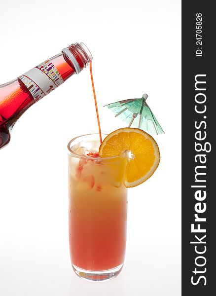 Pouring grenadine into tequila sunrise Cocktail isolated on a white background