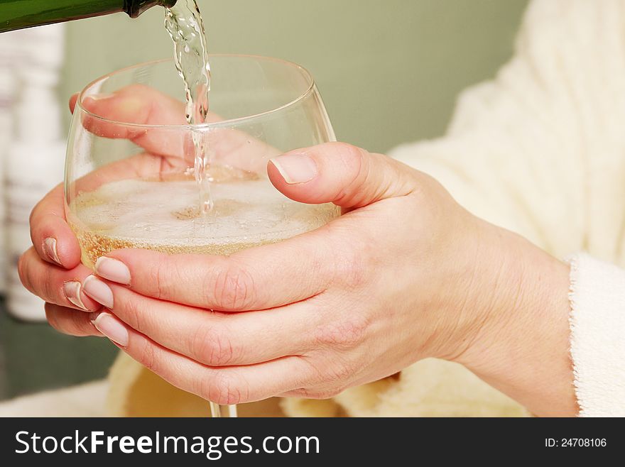 Womans' hands holding wine glass with clear liquid poured. Womans' hands holding wine glass with clear liquid poured.