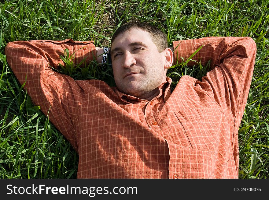 Young man lying on the grass with his hands behind his head