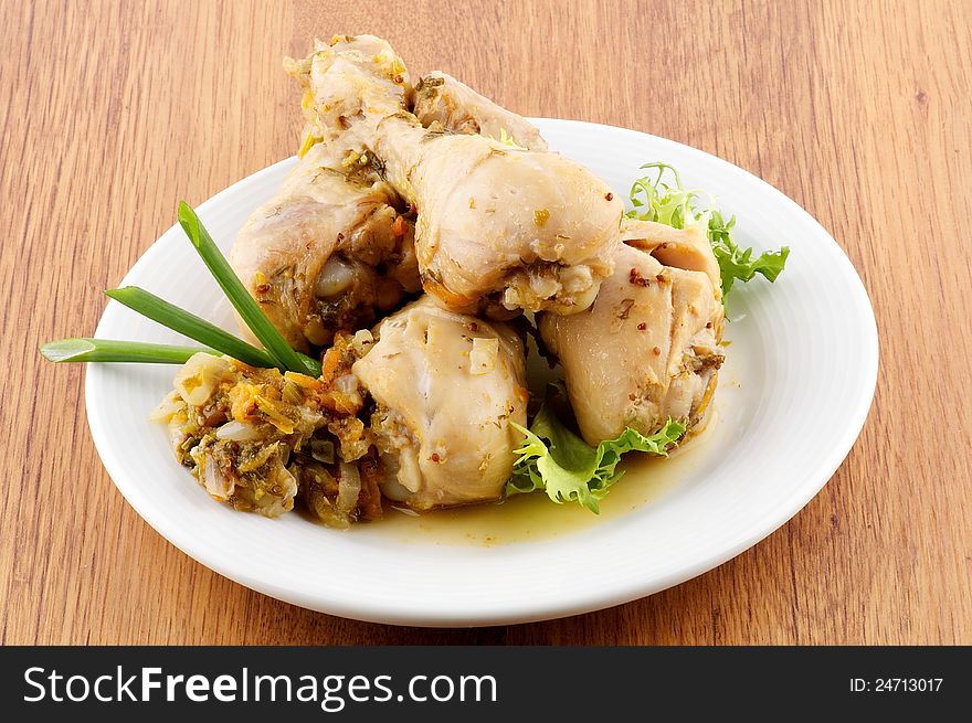 Roasted chicken legs vegetables saute and greens close up on wooden background