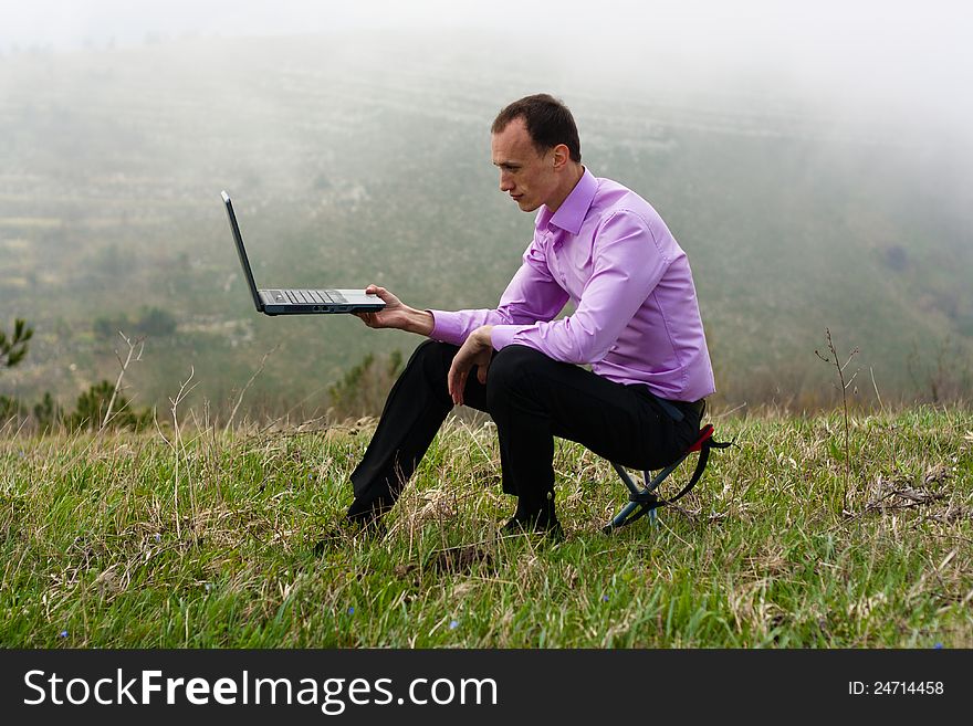 Man on nature keeps in hand computer. Man on nature keeps in hand computer