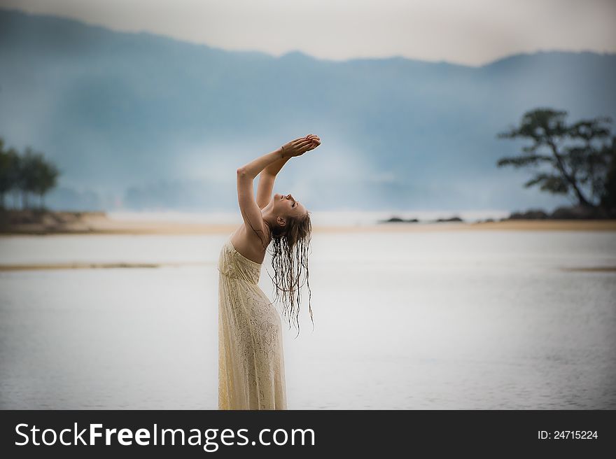 A beautiful young girl in white dress bent in water in Thailand