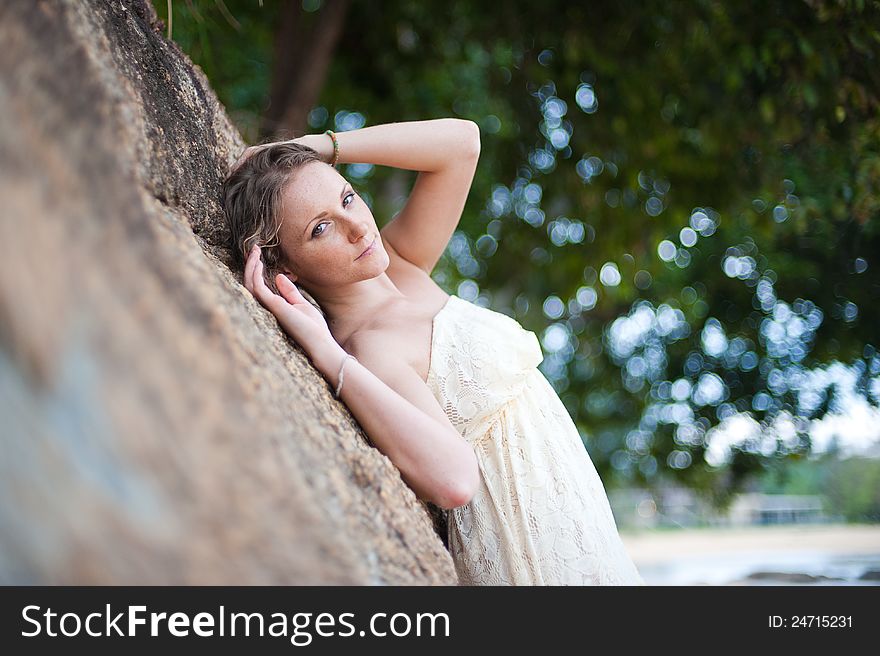 A beautiful young girl in white dress lying on a rock. A beautiful young girl in white dress lying on a rock