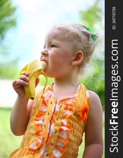 Child eats a banana on the nature