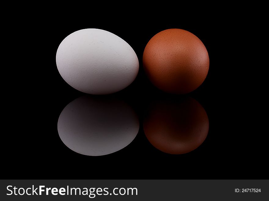 Two chicken eggs on black background.