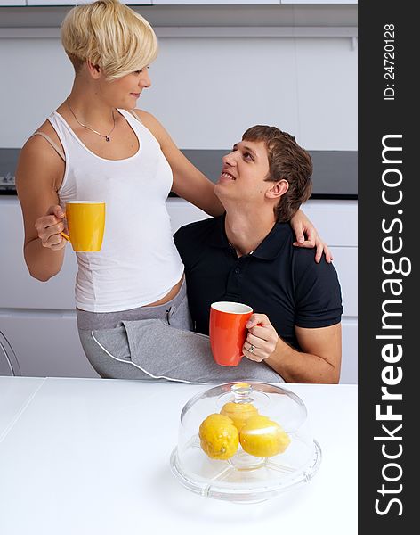 Portrait of a happy couple posing in the kitchen with cups and lemons on the table