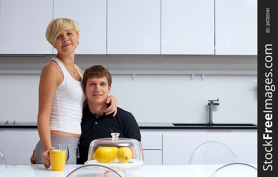 Portrait of a happy couple posing in the kitchen with cups and lemons on the table