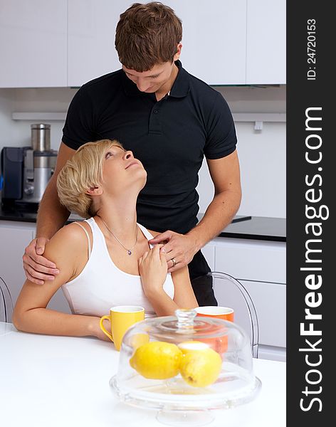 Portrait of a happy couple posing in the kitchen with cups and lemons on the table