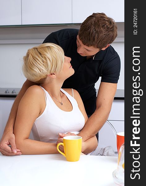 Portrait of a happy couple posing in the kitchen with cups