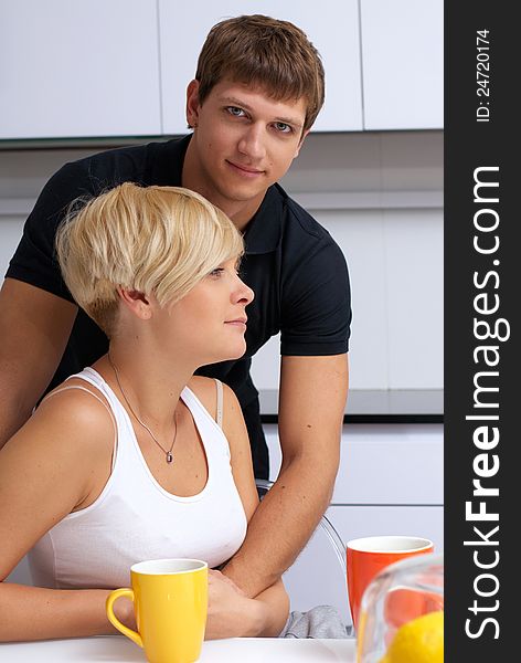 Portrait of a happy couple posing in the kitchen with cups and lemons on the table