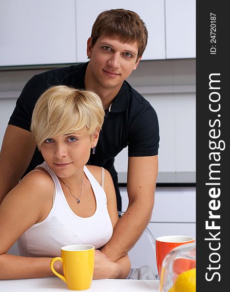 Portrait of a happy couple posing in the kitchen with cups and lemons on the table