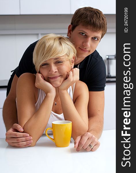 Happy couple posing in the kitchen with cups