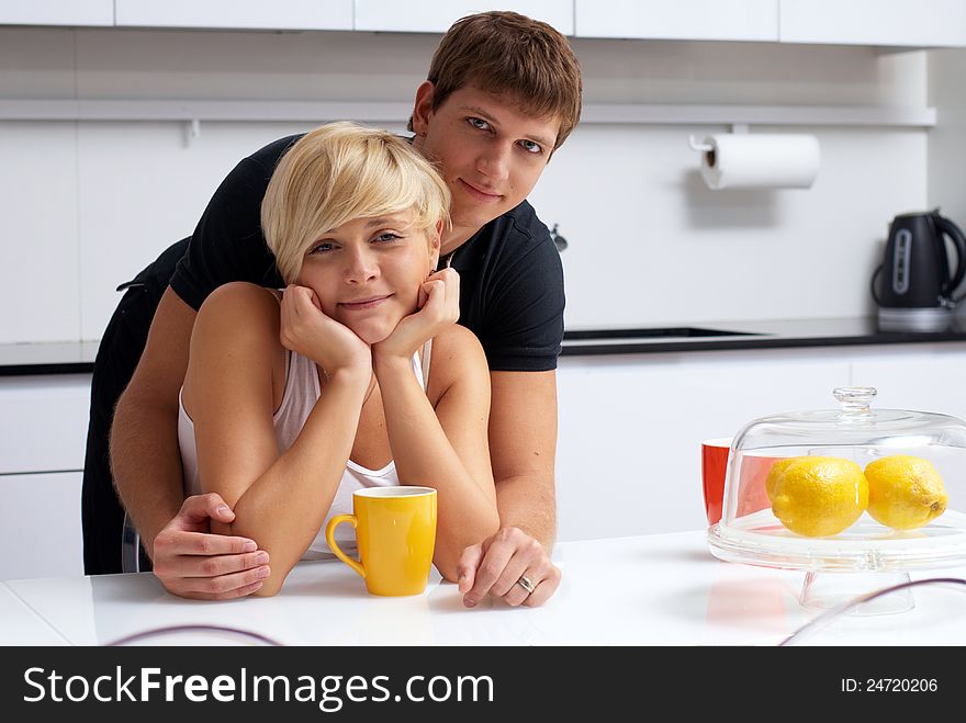 Portrait of a happy couple posing in the kitchen with cups and lemons on the table