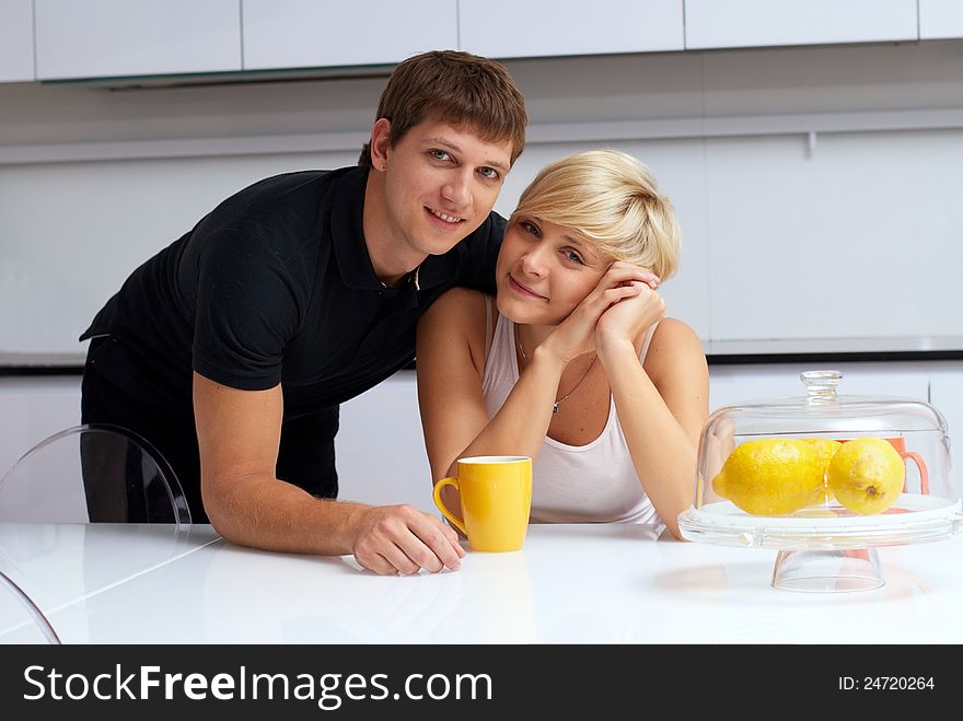 Portrait of a happy couple posing in the kitchen with cups and lemons on the table