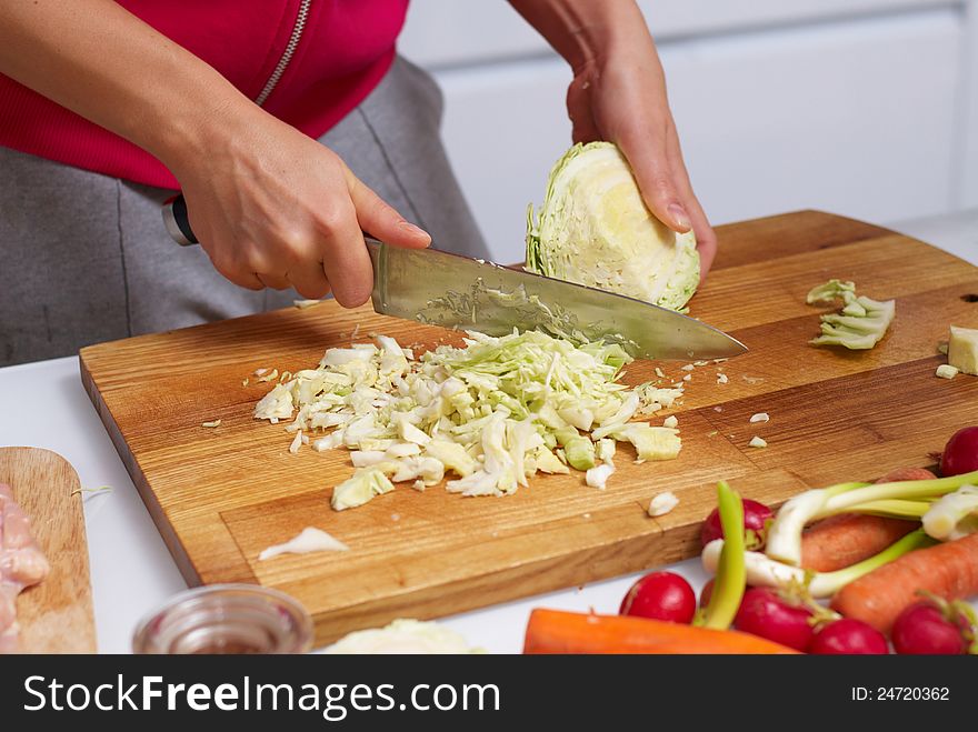 Female hands slicing cabbage on cutting board