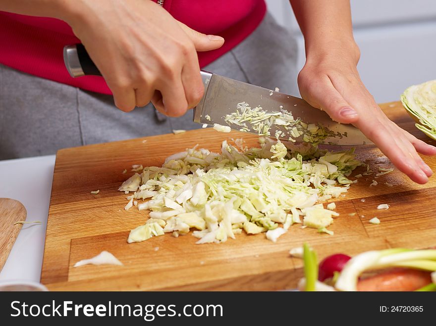Female hands slicing cabbage on cutting board