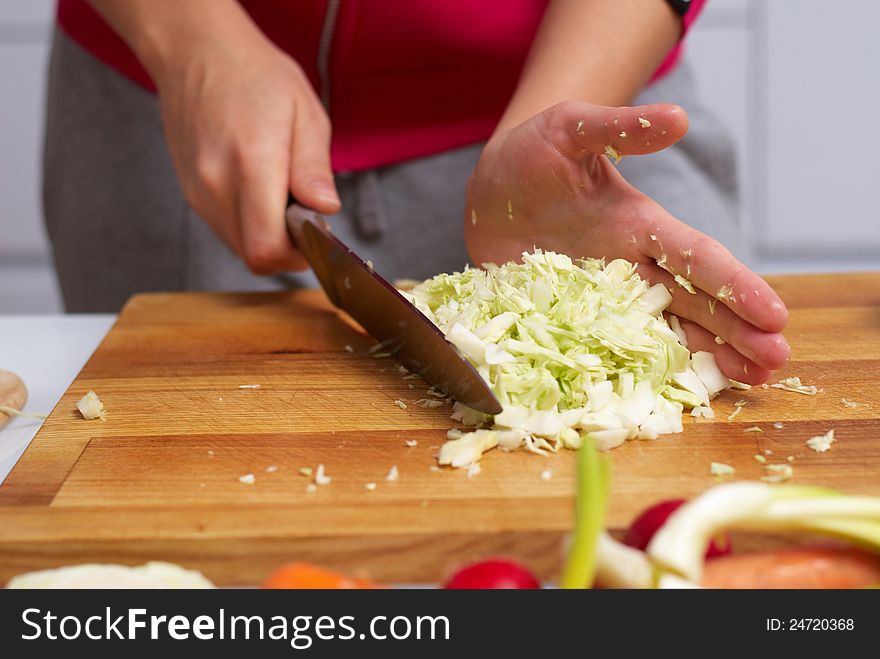 Female hands slicing cabbage