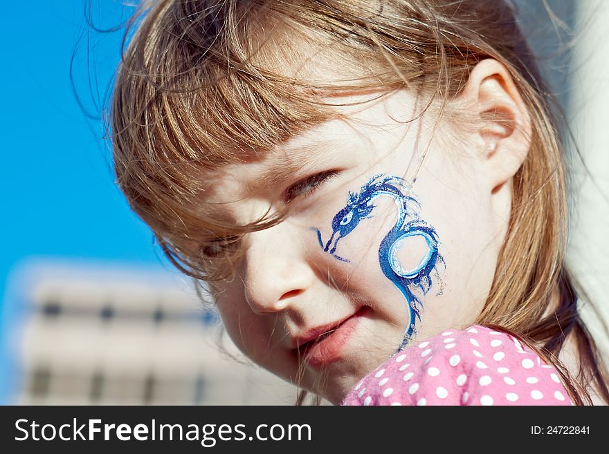 Close-up portrait of a little girl with blue dragon on her face. Close-up portrait of a little girl with blue dragon on her face