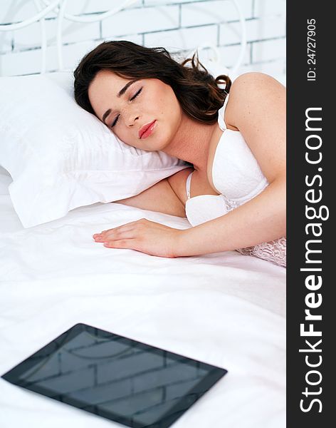 Beautiful emotional young woman using tablet computer in her bedroom high key. Beautiful emotional young woman using tablet computer in her bedroom high key