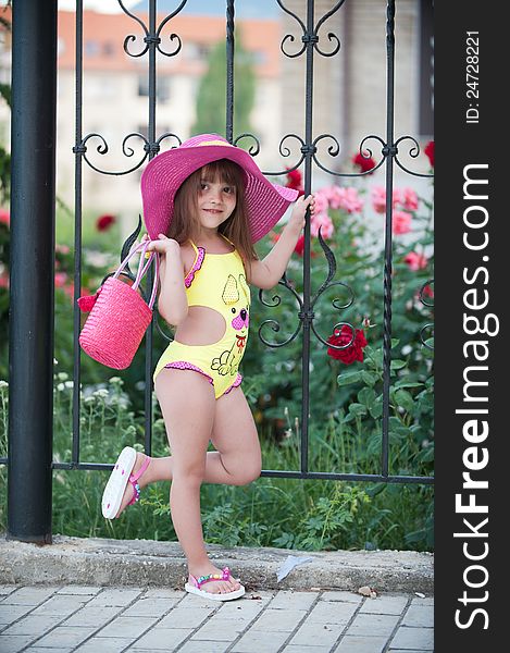 Picture a cute little girl in hat posing with beautiful flowerbeds. Picture a cute little girl in hat posing with beautiful flowerbeds