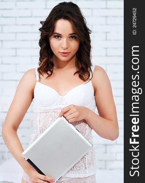 Beautiful emotional young woman using tablet computer in her bedroom high key. Beautiful emotional young woman using tablet computer in her bedroom high key