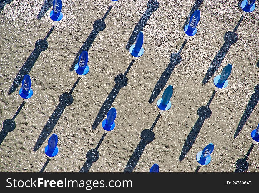 Blue beach umbrellas casting shadows on the beach