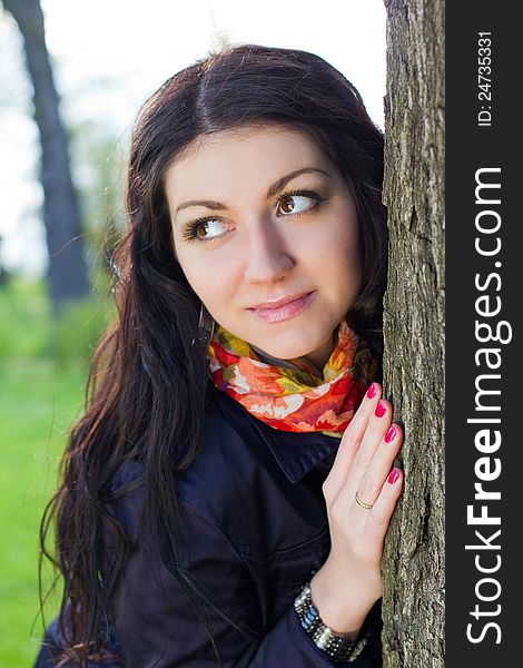 Beautiful young girl near tree in the park