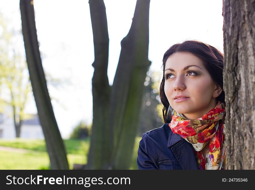 Beautiful young girl near tree in the park