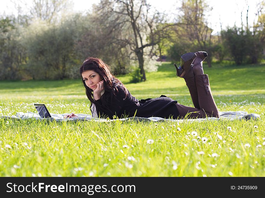 Young woman working with net-book outdoors in park on grass. Young woman working with net-book outdoors in park on grass