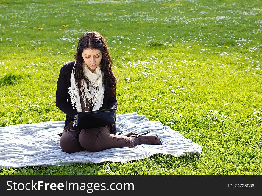 Young woman working with net-book outdoors in park on grass. Young woman working with net-book outdoors in park on grass