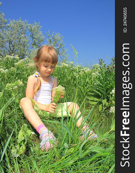 A little girl sits in the grass