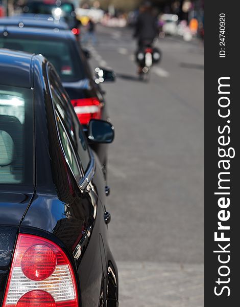 Parked cars along the city road with a cyclist out of focus in the background. Parked cars along the city road with a cyclist out of focus in the background