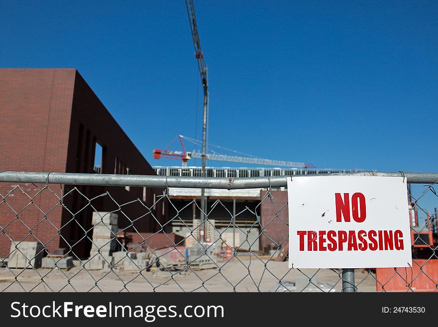 Image of a cluttered construction site that is fenced with a warning sign No trespassing