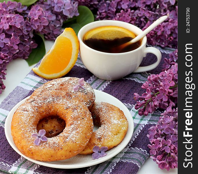 Sweet cottage cheese donuts with orange tea for breakfast and lilac flowers on the table. Sweet cottage cheese donuts with orange tea for breakfast and lilac flowers on the table