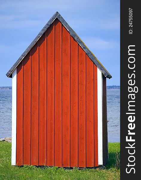 Red boathouse with blue sky and water in background