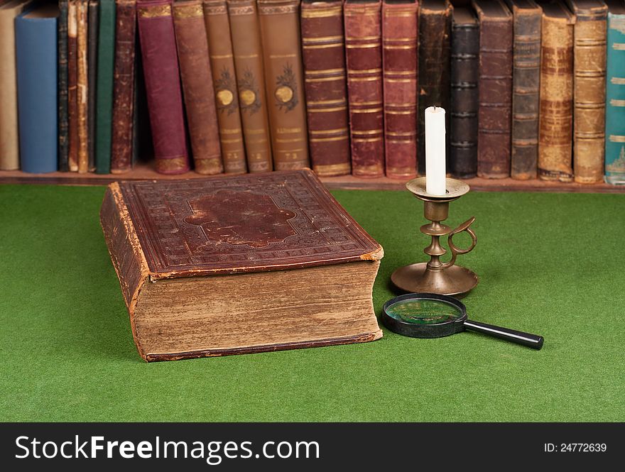 Antique book, candlestick and magnifying glass