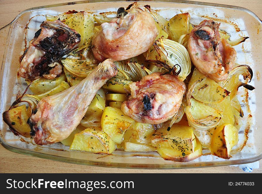 Roasted chicken with baked potatoes in a glass ovenproof dish