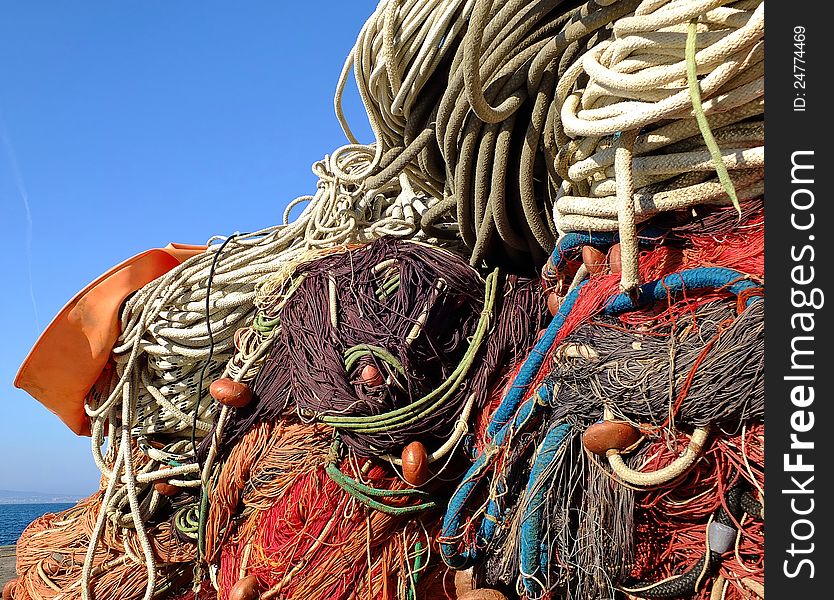 Fishing nets and ropes colored by a multitude of shades of blue, red, orange, green on a clear blue sky and sea background. Fishing nets and ropes colored by a multitude of shades of blue, red, orange, green on a clear blue sky and sea background