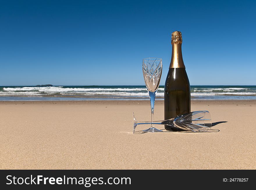 Bottle of champagne with two crystals glasses on a secluded beach. Bottle of champagne with two crystals glasses on a secluded beach.